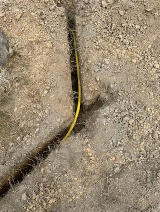 A yellow wire is laying in the dirt.