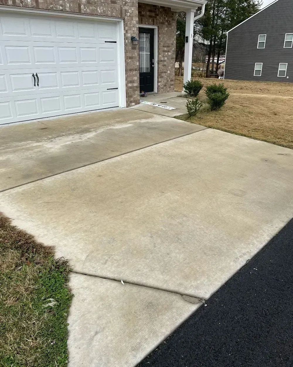 A concrete driveway leads to the garage door and front entryway of a residential home.