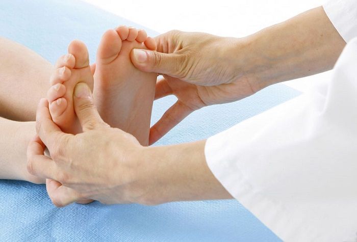 Una persona riceve un massaggio ai piedi da un medico.