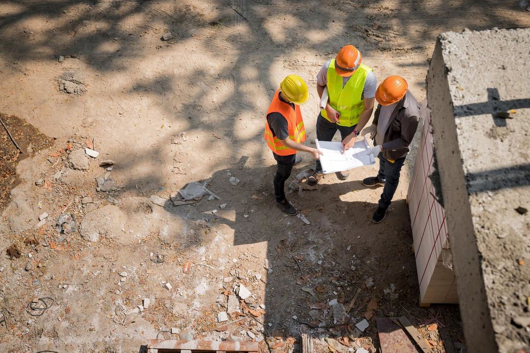 A group of construction workers are looking at a blueprint on a construction site.
