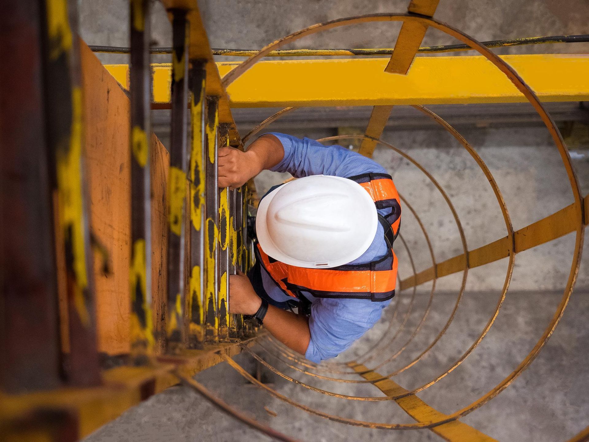 A construction worker is climbing up a spiral staircase.