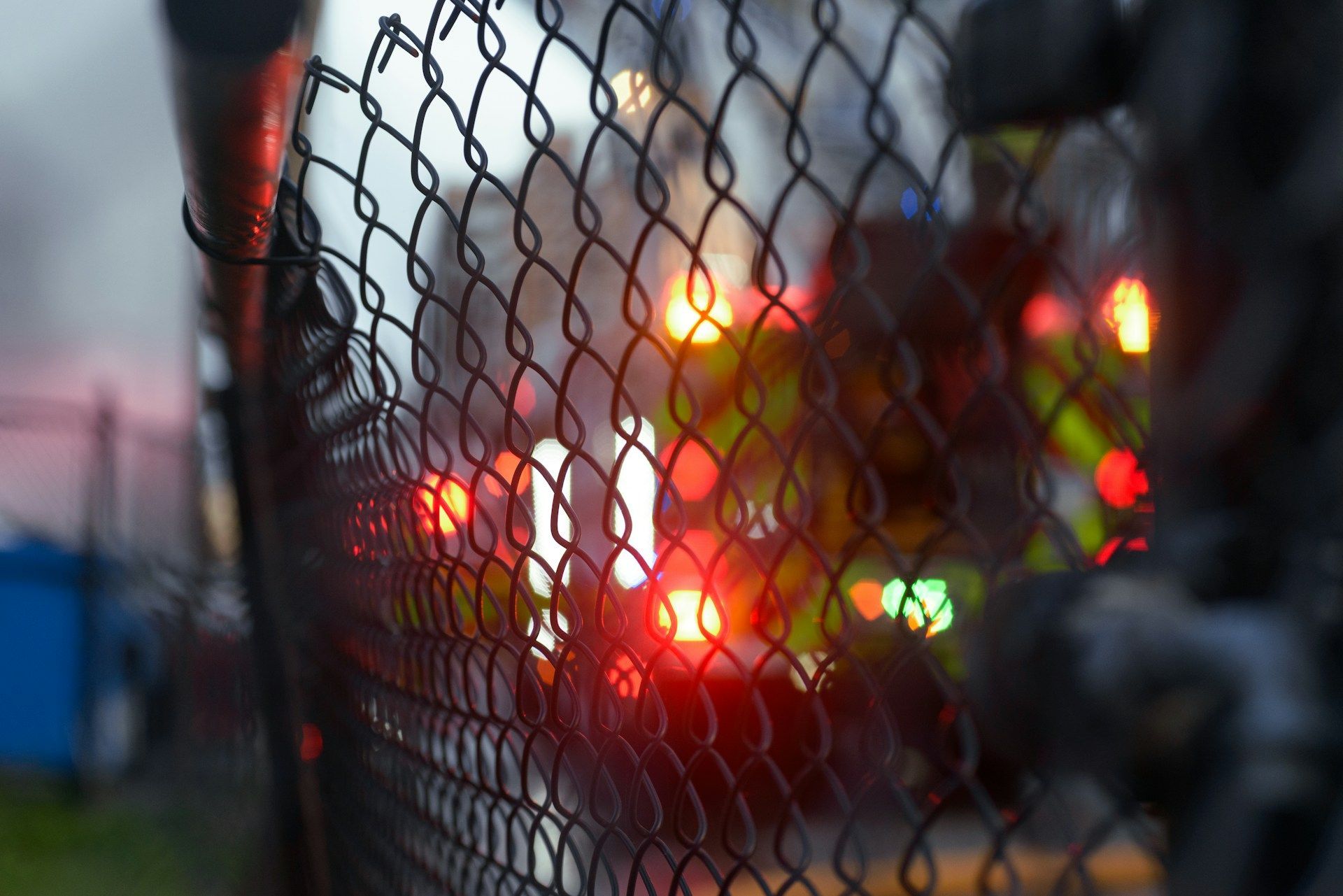 A chain link fence with a blurry picture of a fire truck behind it.
