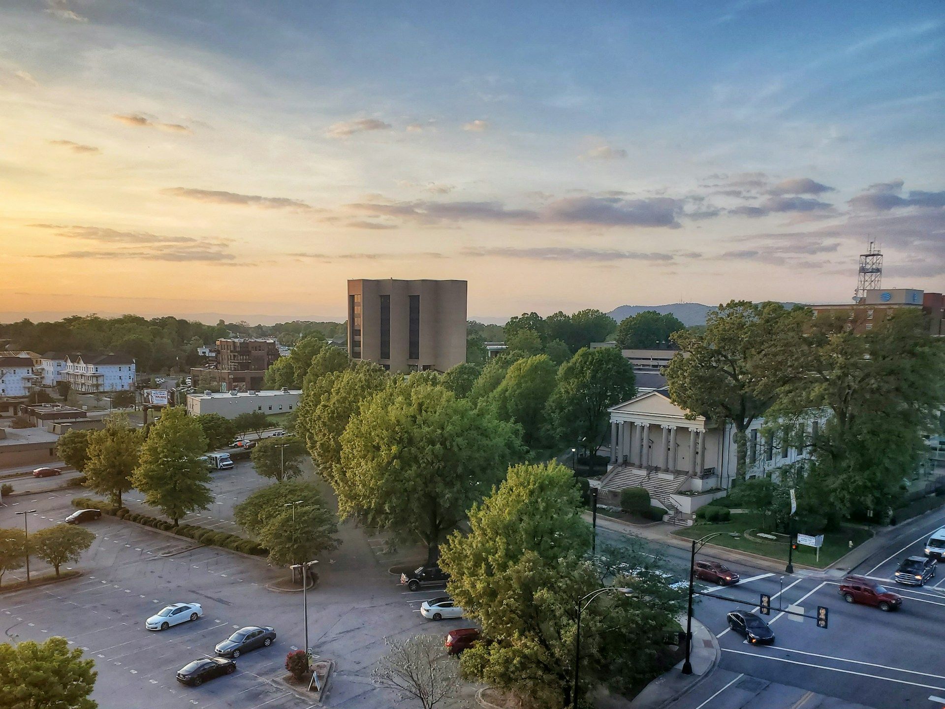 An aerial view of a city at sunset with cars parked in a parking lot.