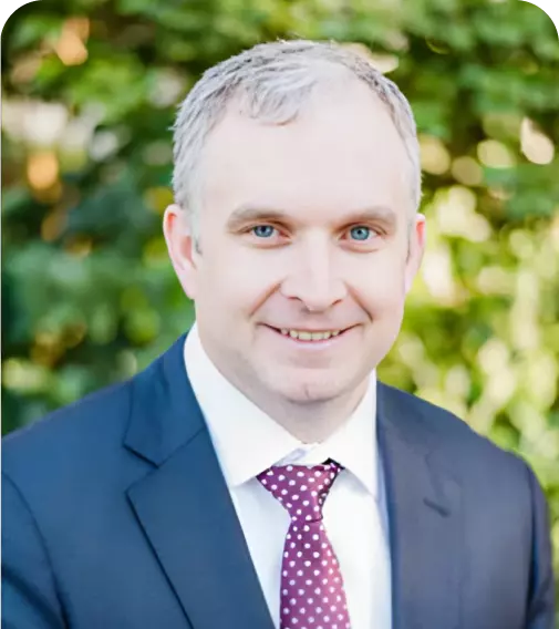 A man in a suit and tie is smiling for the camera