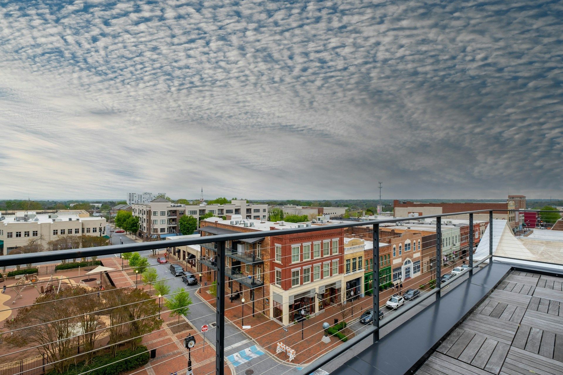An aerial view of a city from a balcony with a cloudy sky in the background.