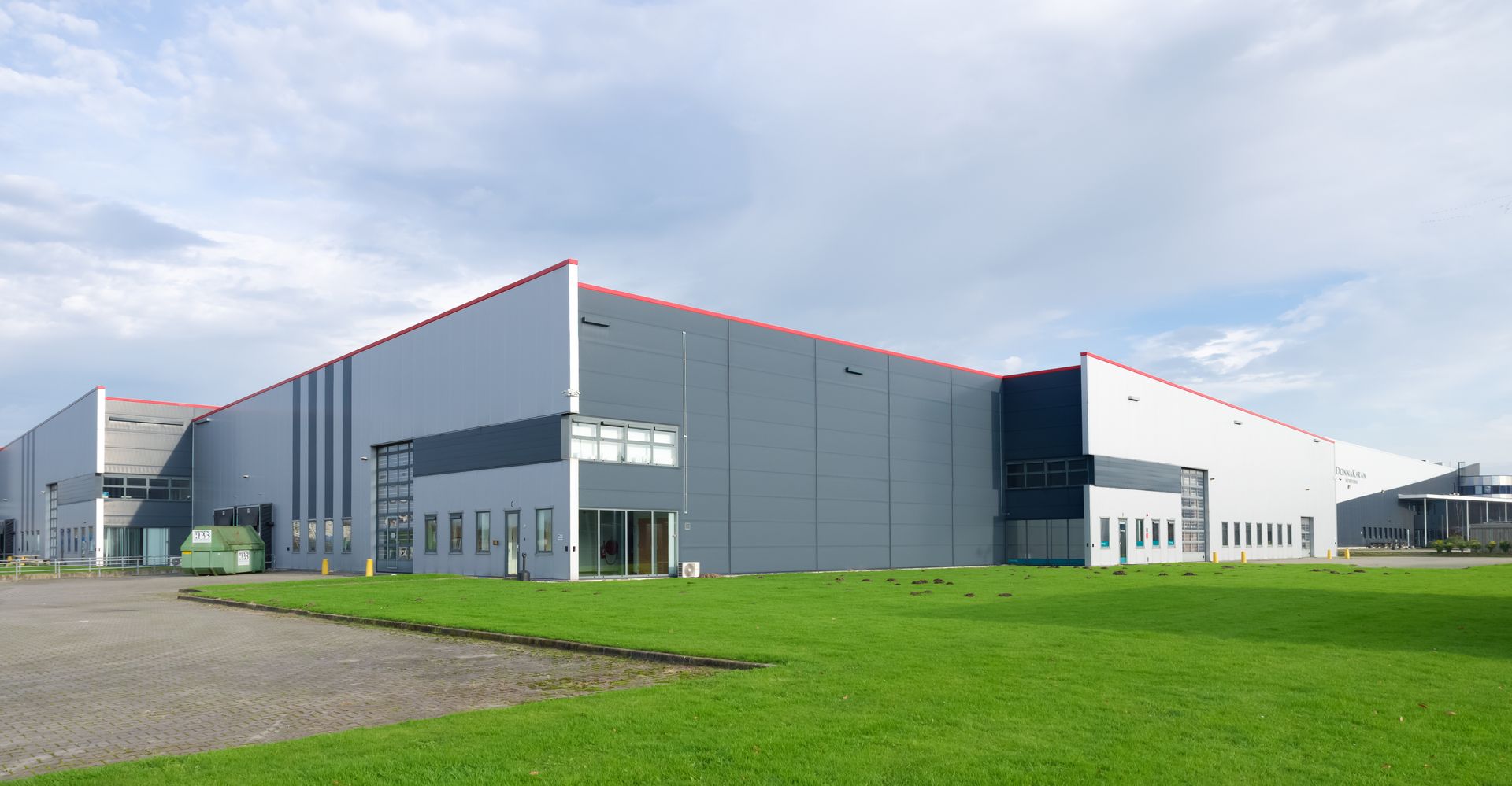 Exterior view of a recently renovated large industrial warehouse with a fresh coat of white and gray paint.