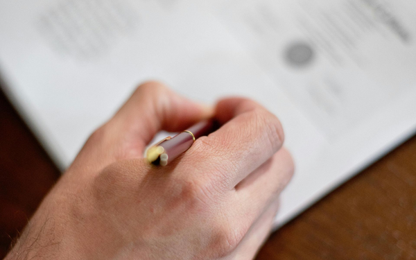 Hand with pen signing contract.