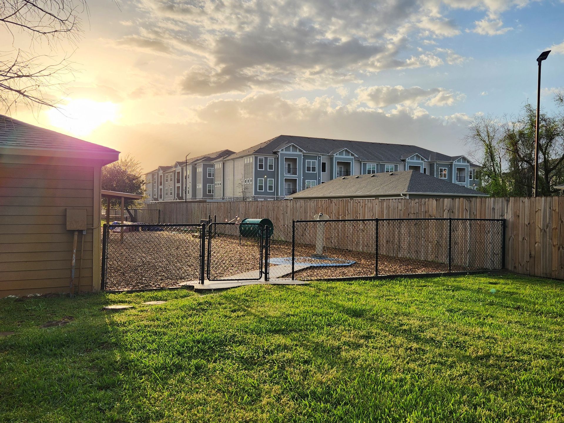A backyard with a chain link fence and a house in the background.