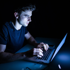 guy looking at computer in dark room