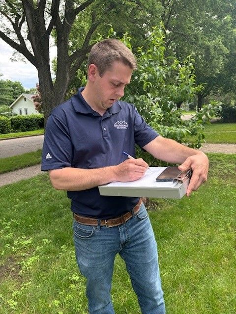 A man in a blue shirt is writing on a piece of paper