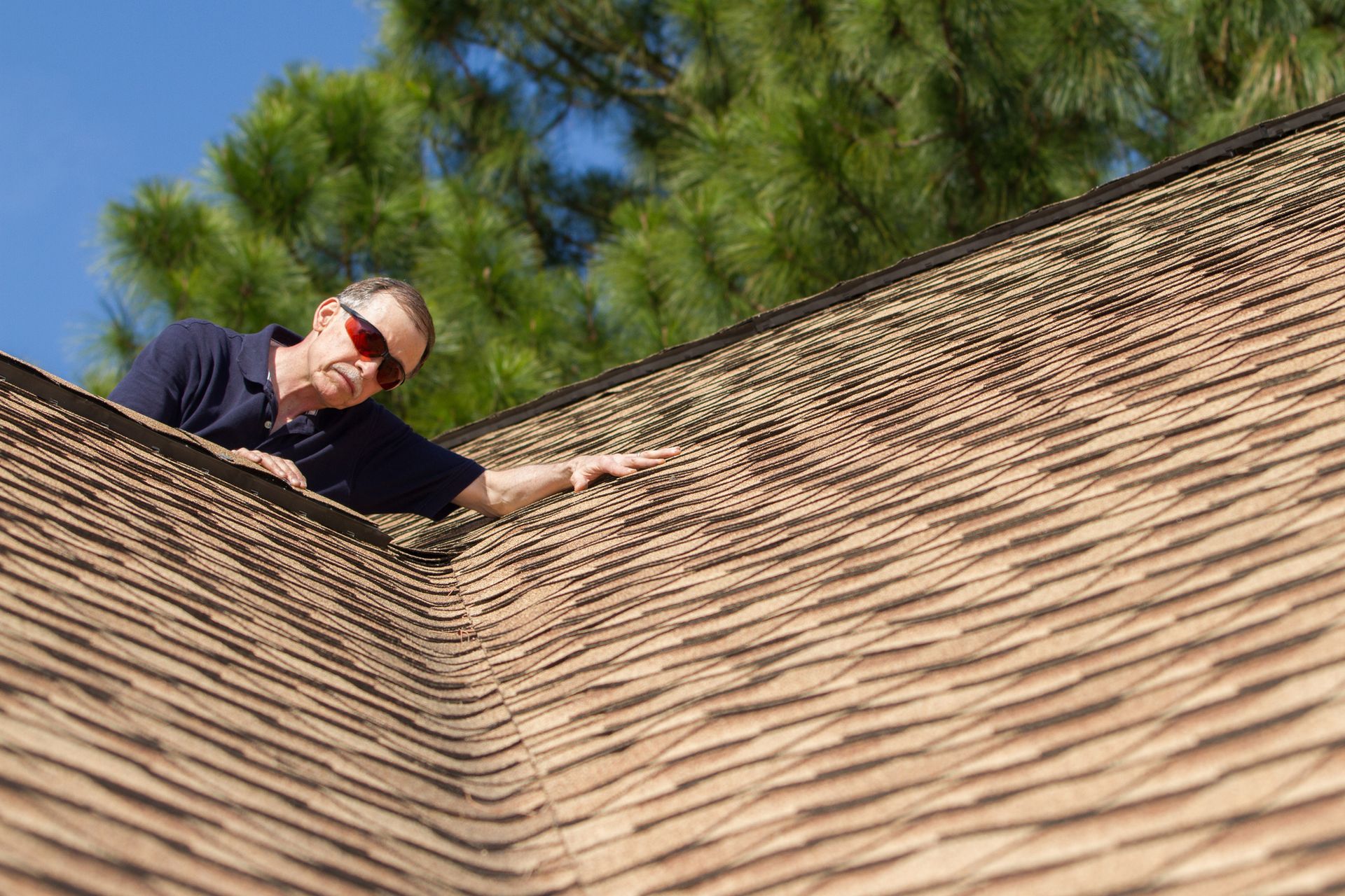 An inspector looks down a roof valley at shingles on a home. An inspector looks down a roof valley at shingles on a home.
