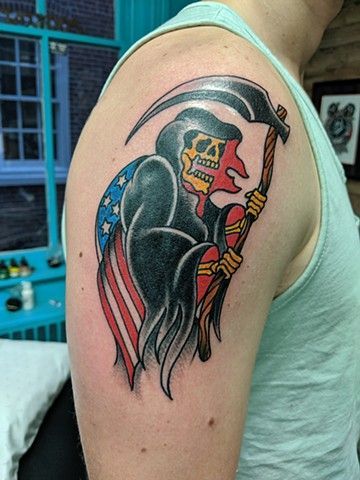 A man has a tattoo of a grim reaper holding an american flag on his shoulder.