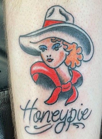 A tattoo of a woman wearing a cowboy hat and a red scarf