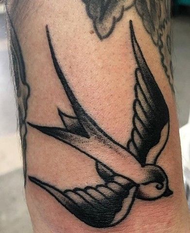 A black and white tattoo of a bird on a person 's arm.