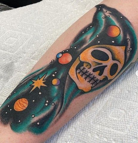 A tattoo of a skull with planets in the background on a person 's arm.