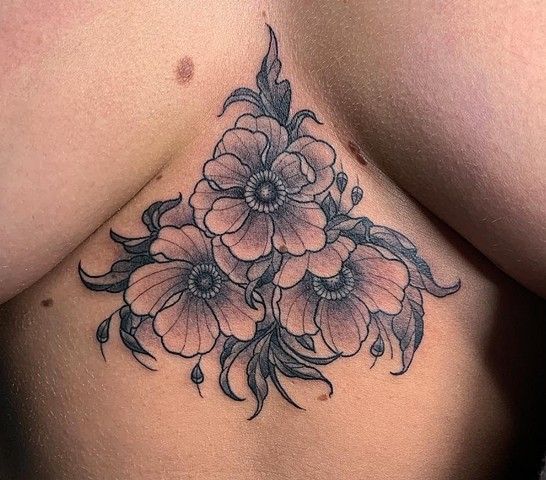 A woman has a tattoo of three flowers on her chest.