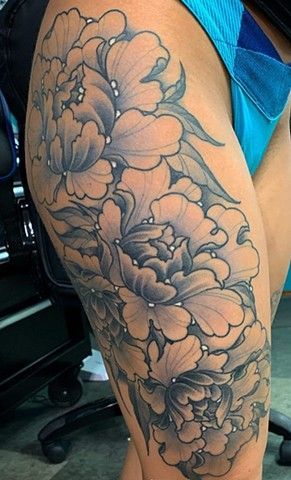 A woman has a tattoo of flowers on her thigh.