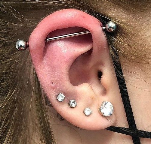 A close up of a woman 's ear with multiple piercings.