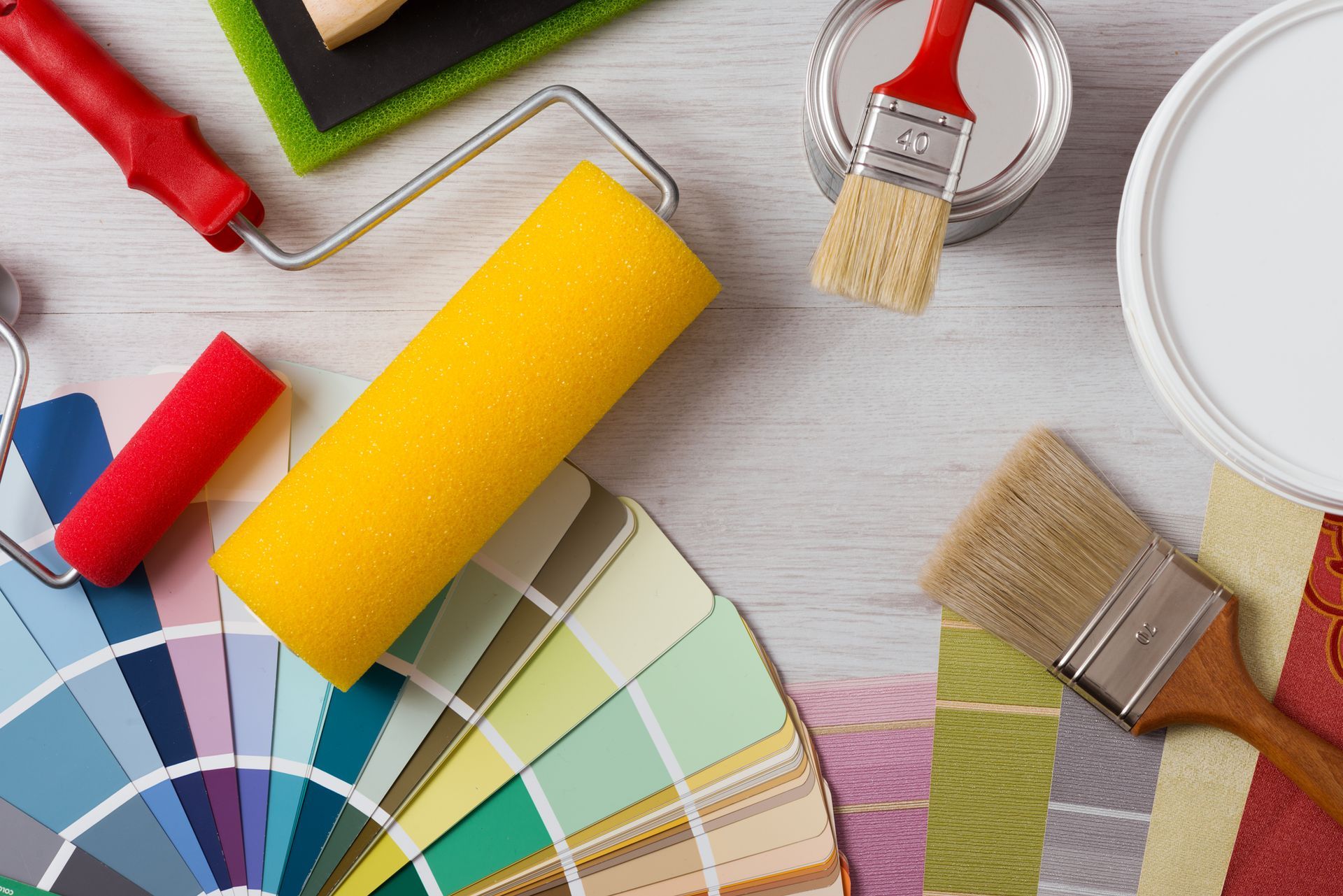 A bunch of paint rollers , brushes , and paint samples on a table.