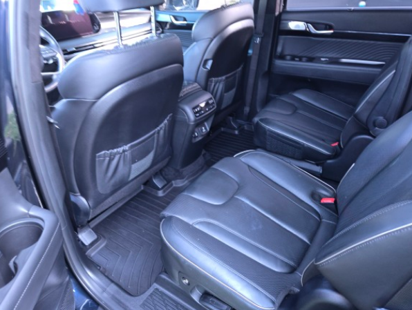 A black bmw x5 is parked in a driveway next to a white van.