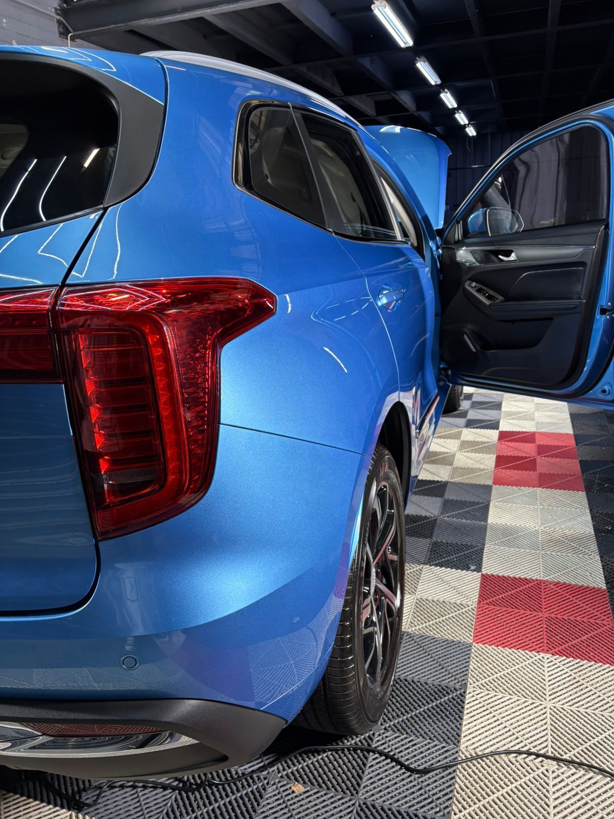 Blue SUV with open door, parked on a patterned floor.
