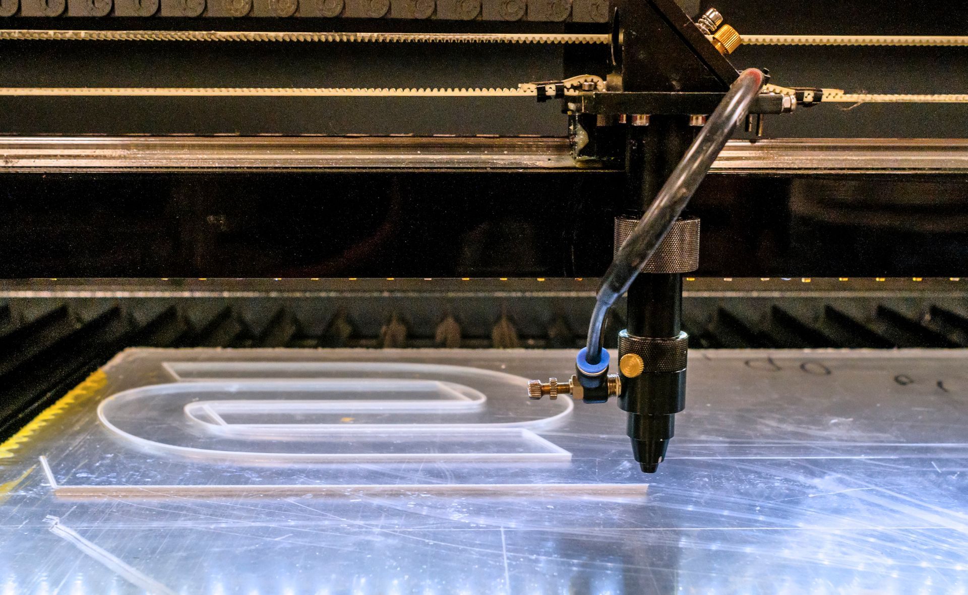 Laser cutting machine working on a clear acrylic sheet.