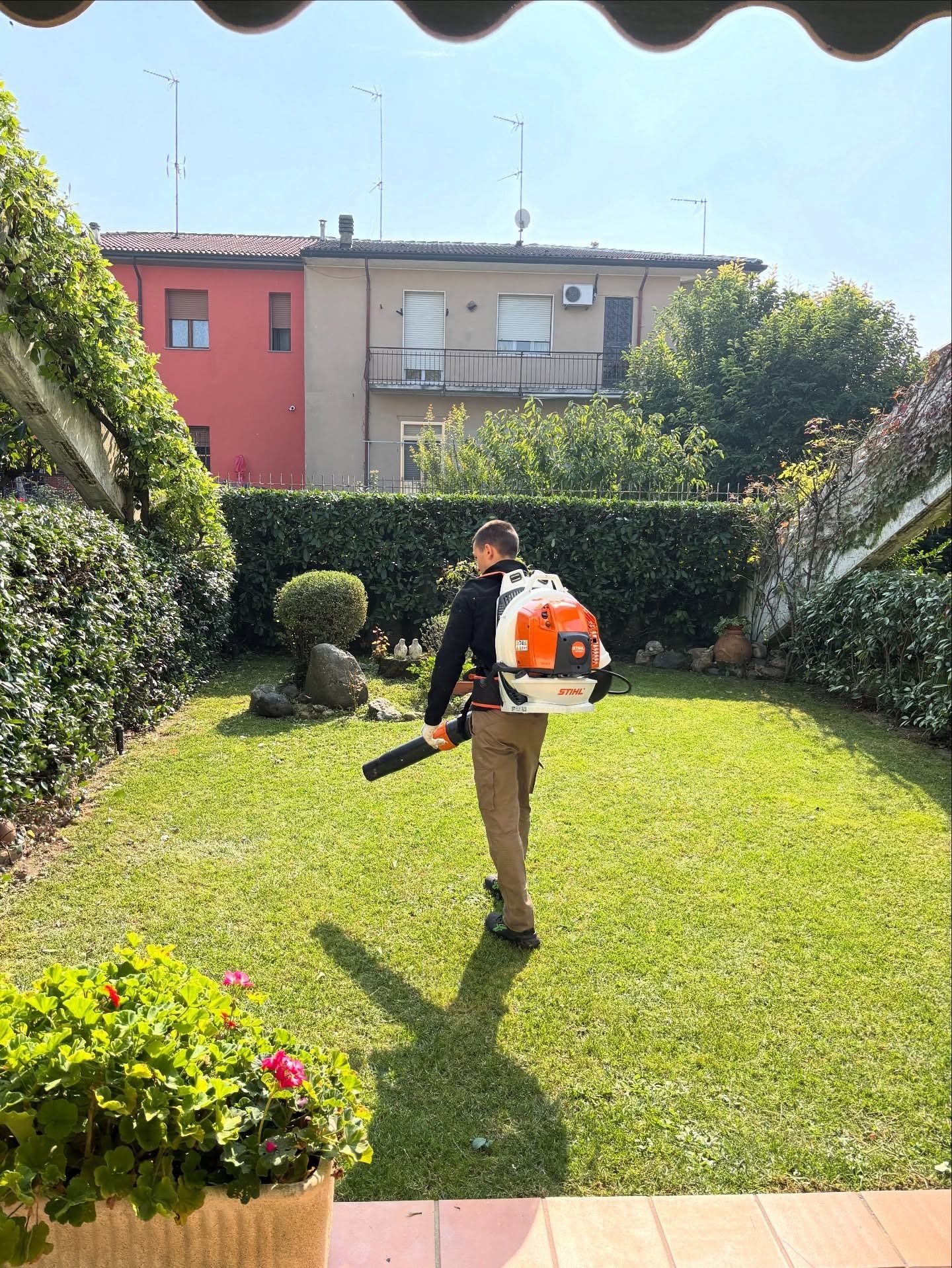 Un operaio utilizza un soffiatore a zaino per pulire il prato di una casa.