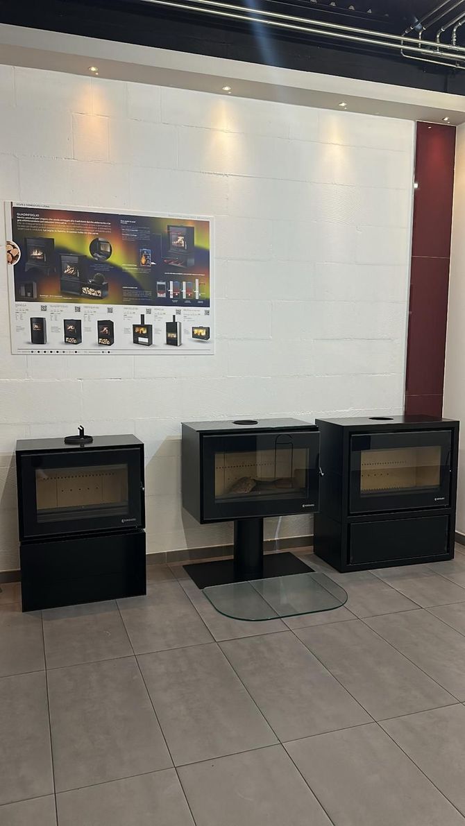 Tre caminetti neri esposti in uno showroom, con un poster del prodotto sulla parete.