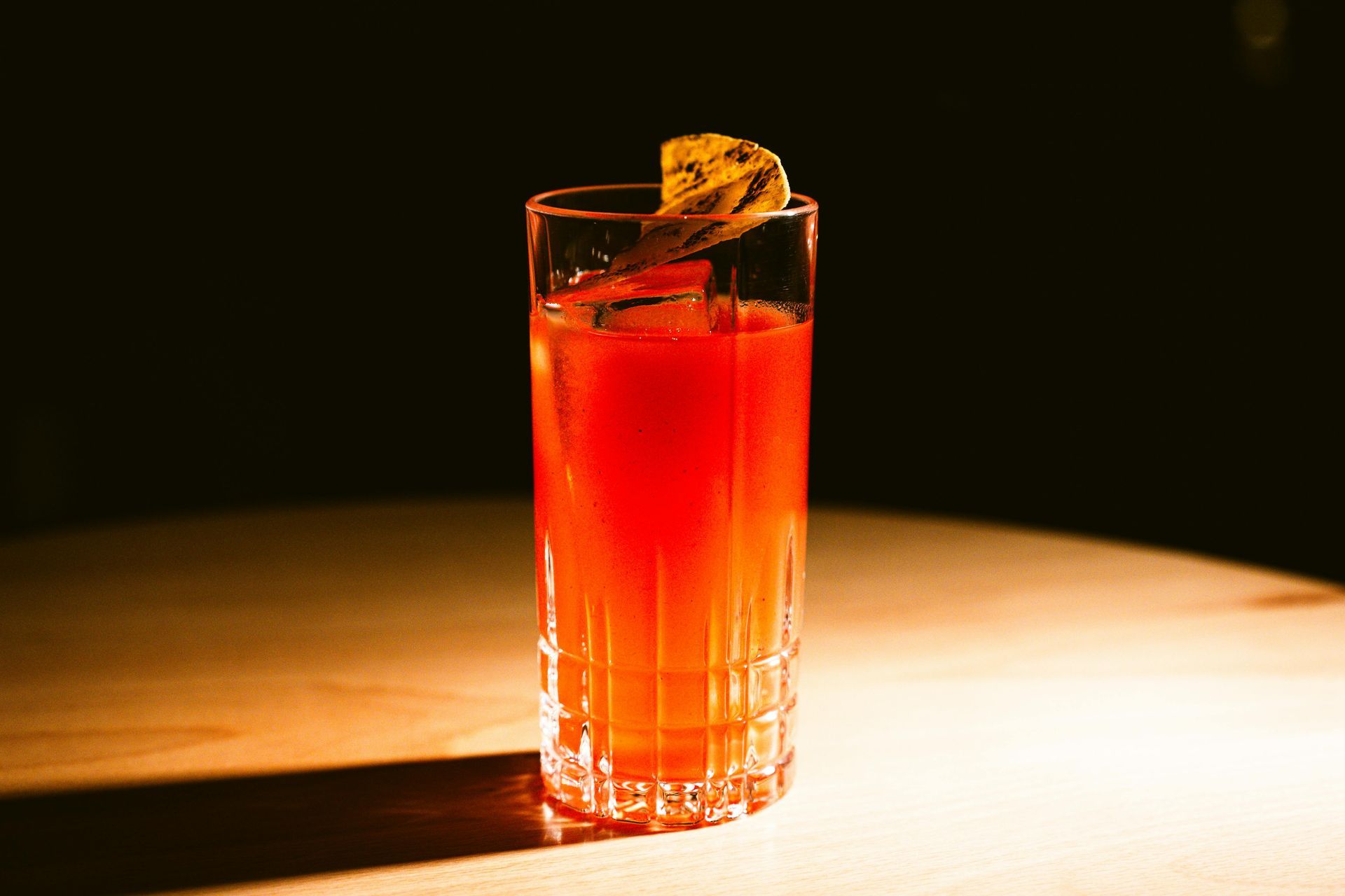 Cocktail garnished with a fuchsia flower and orange slice, being decorated with small skewers.