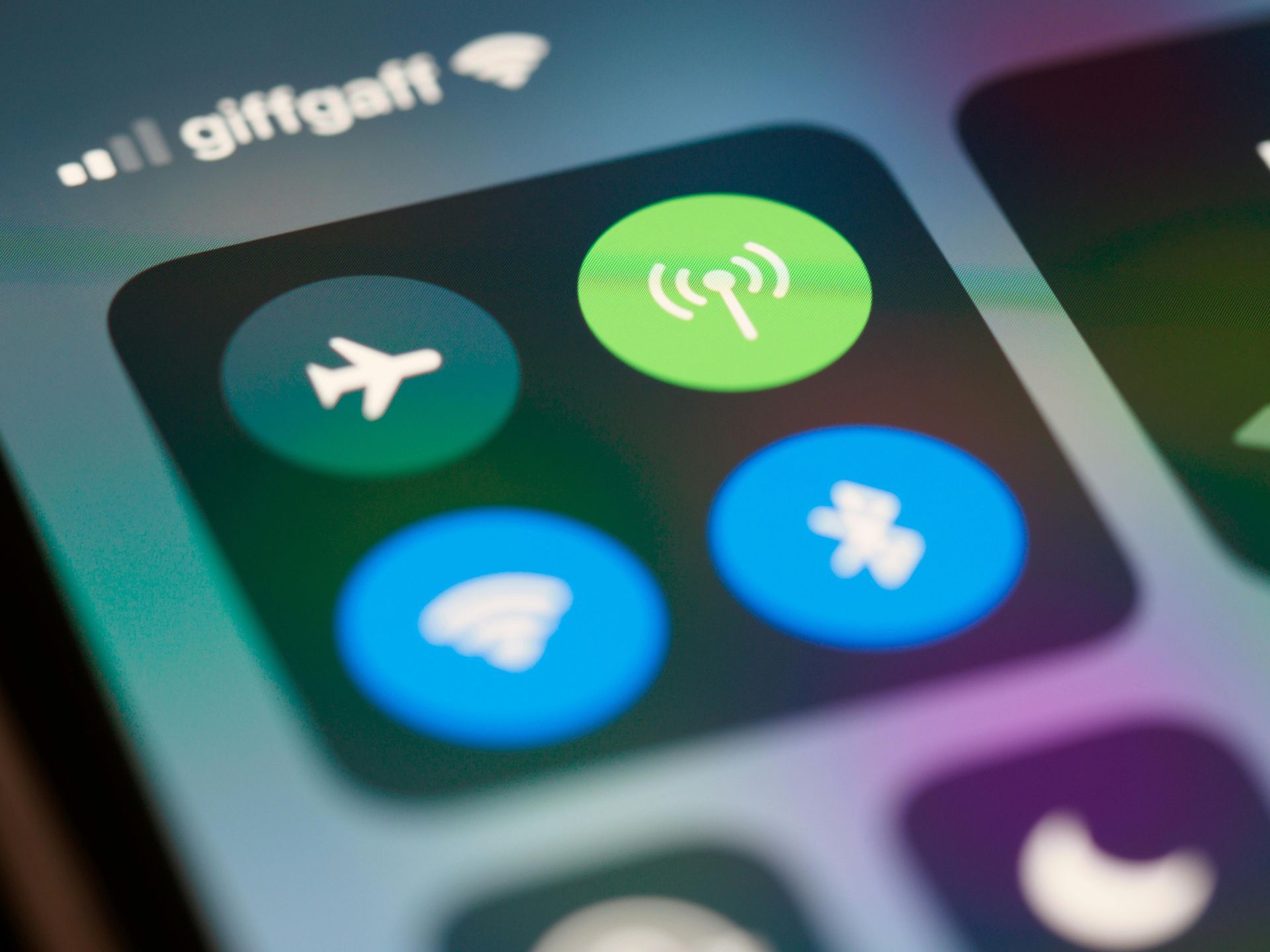 Man smiles while using a tablet at an outdoor table with a drink nearby.