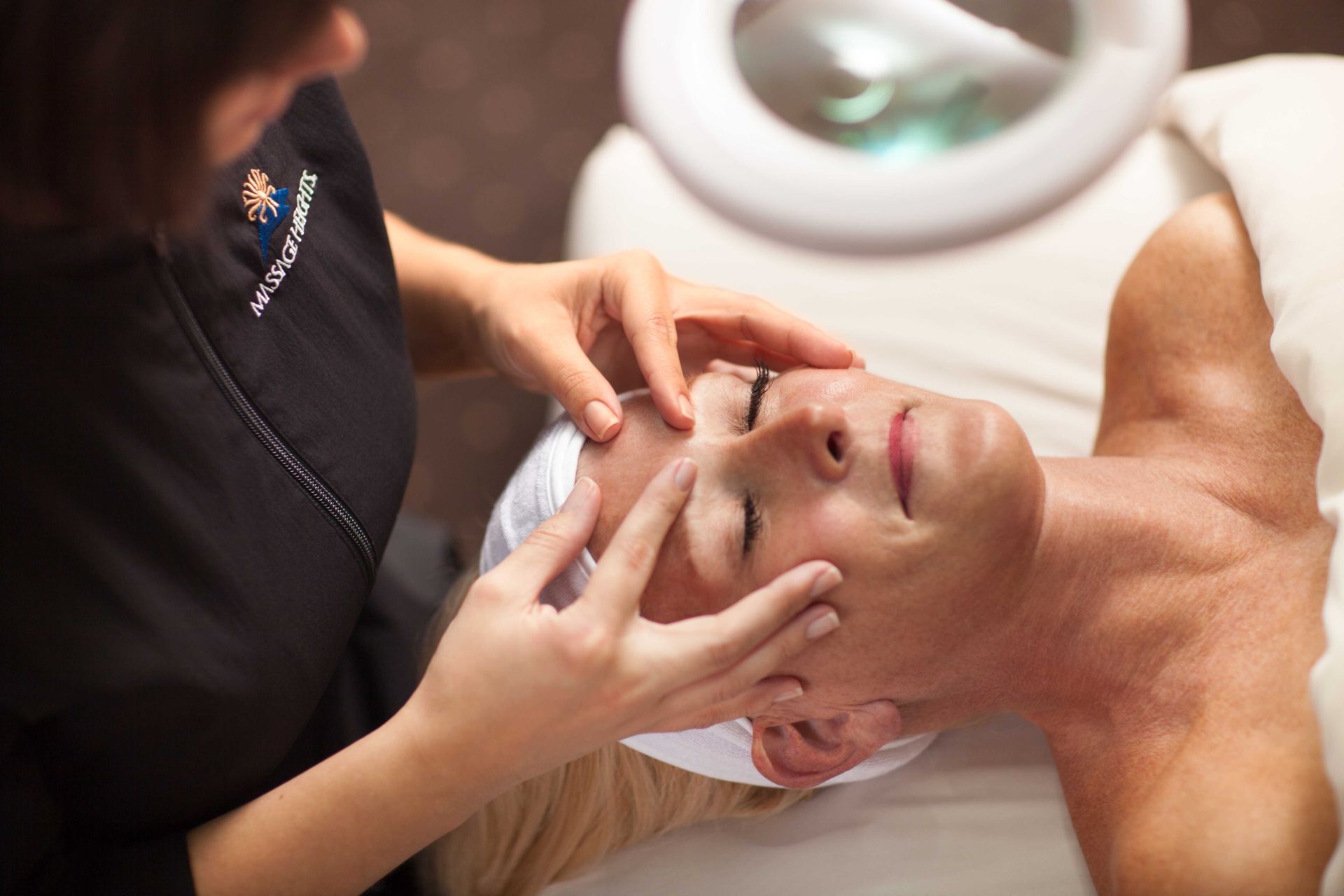 Esthetician performing a facial skin consultation at Massage Heights