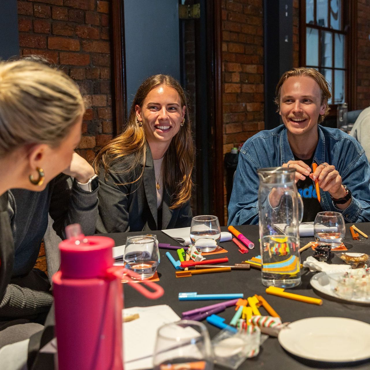 A group of people are sitting around a table with a pink water bottle.