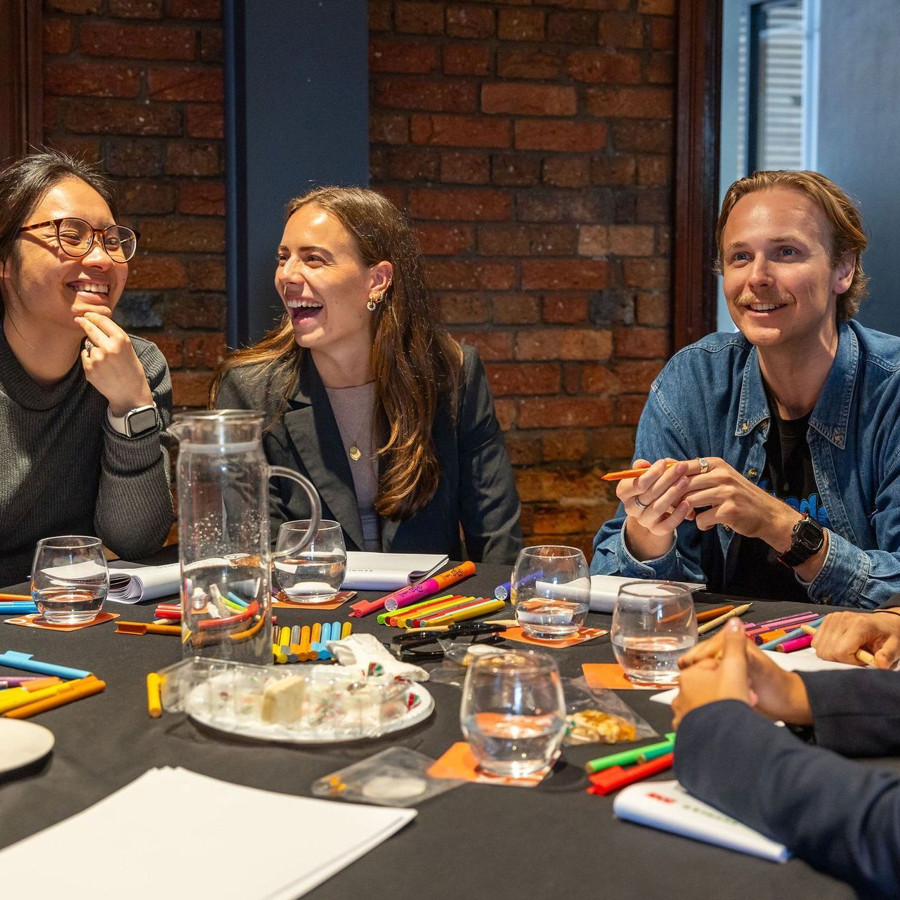 A group of people are sitting around a table laughing