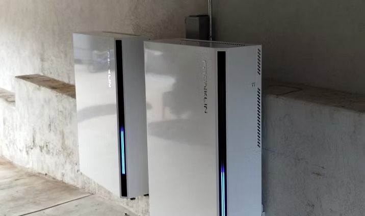 Two white rectangular electronic devices with blue lights, mounted on a wall.