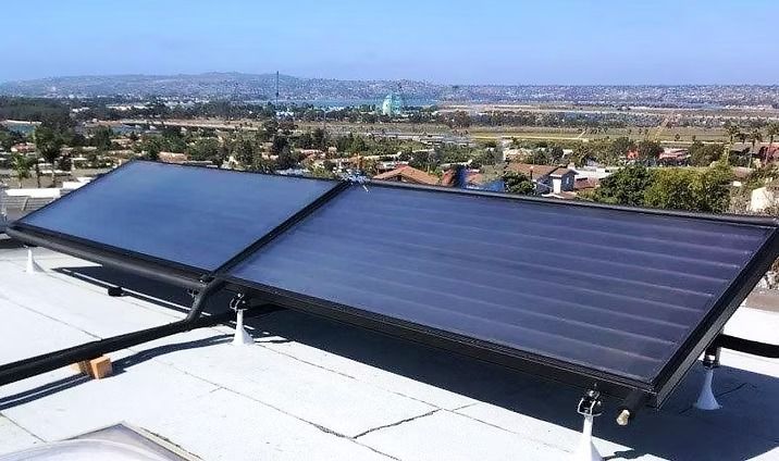 Solar panels on a rooftop, with a city skyline in the background on a sunny day.