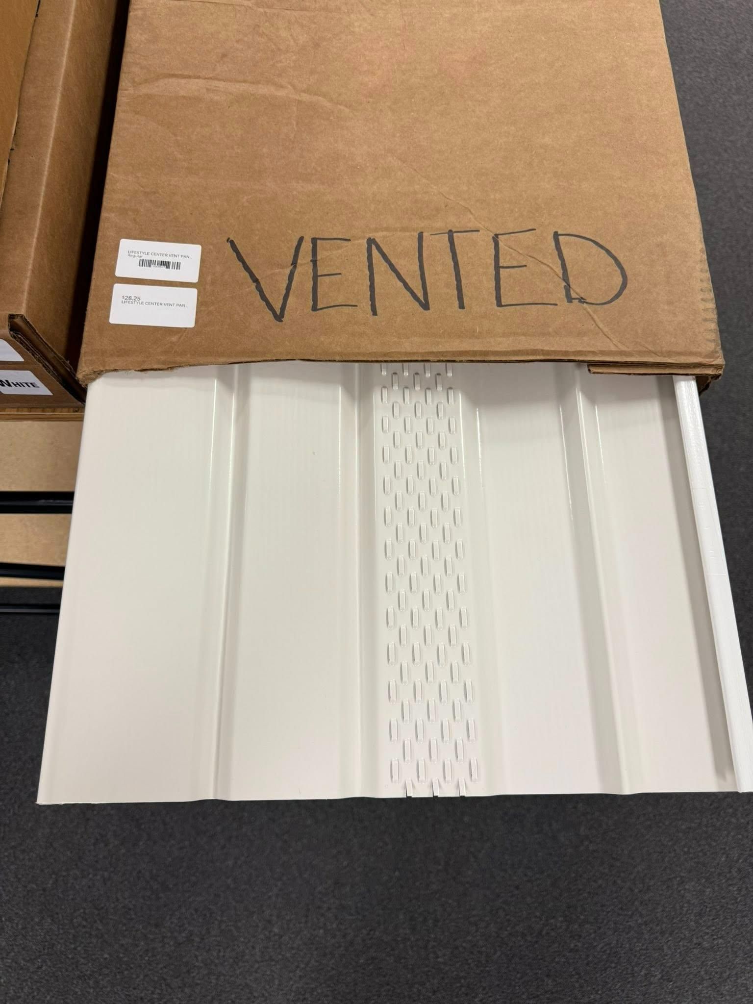 White vented siding panel in a cardboard box.
