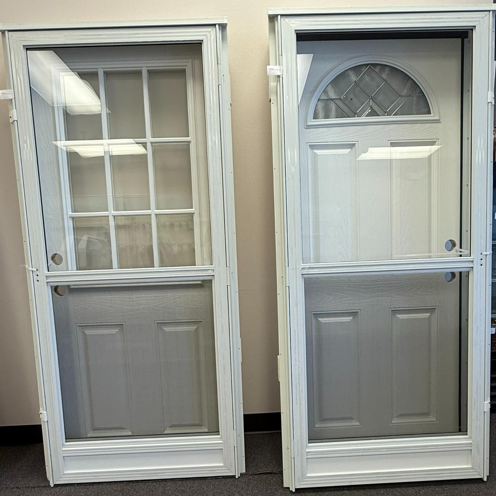 Two white screen doors: one with grid window, one with arched window, on display.