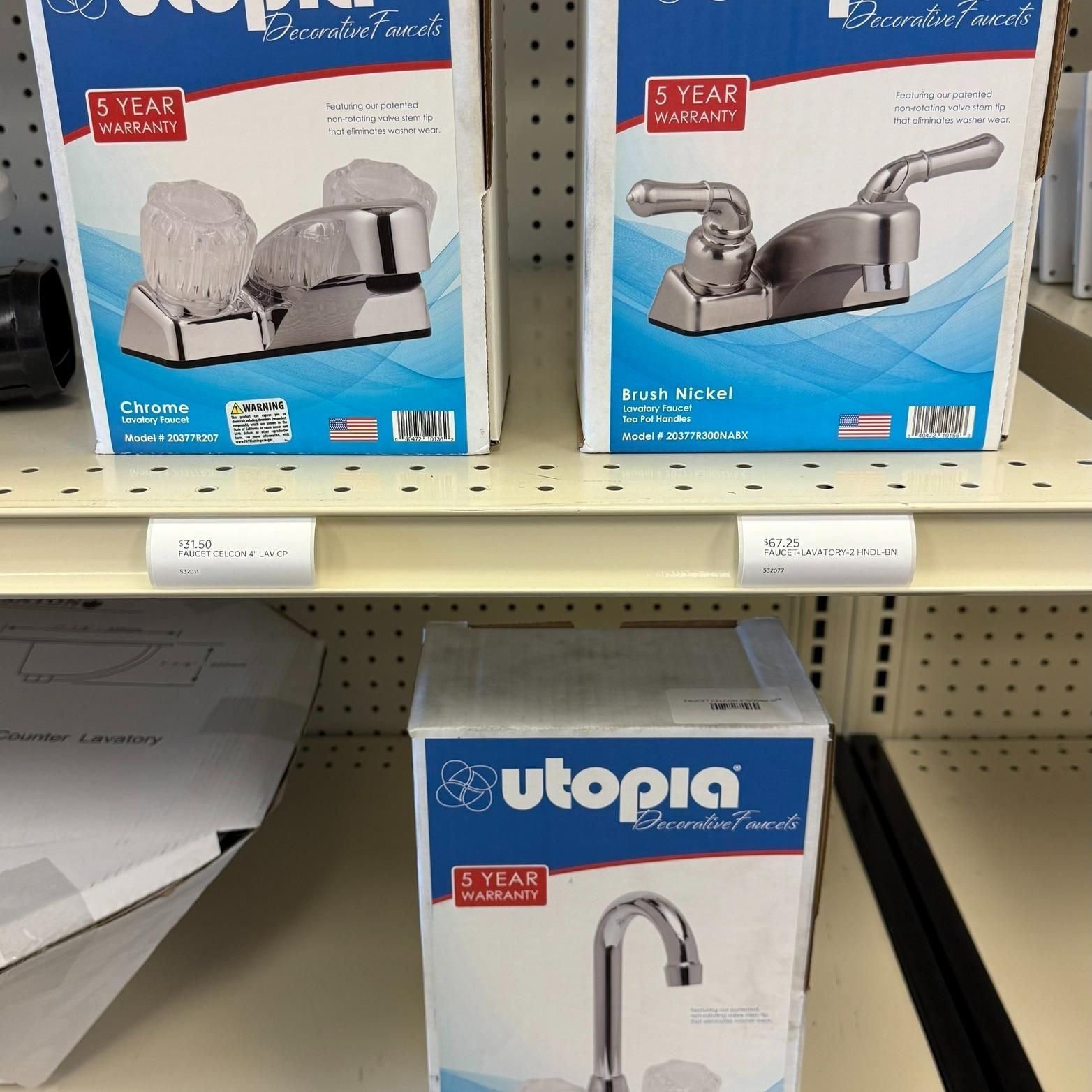 Boxes of Utopia brand bathroom faucets on a store shelf.
