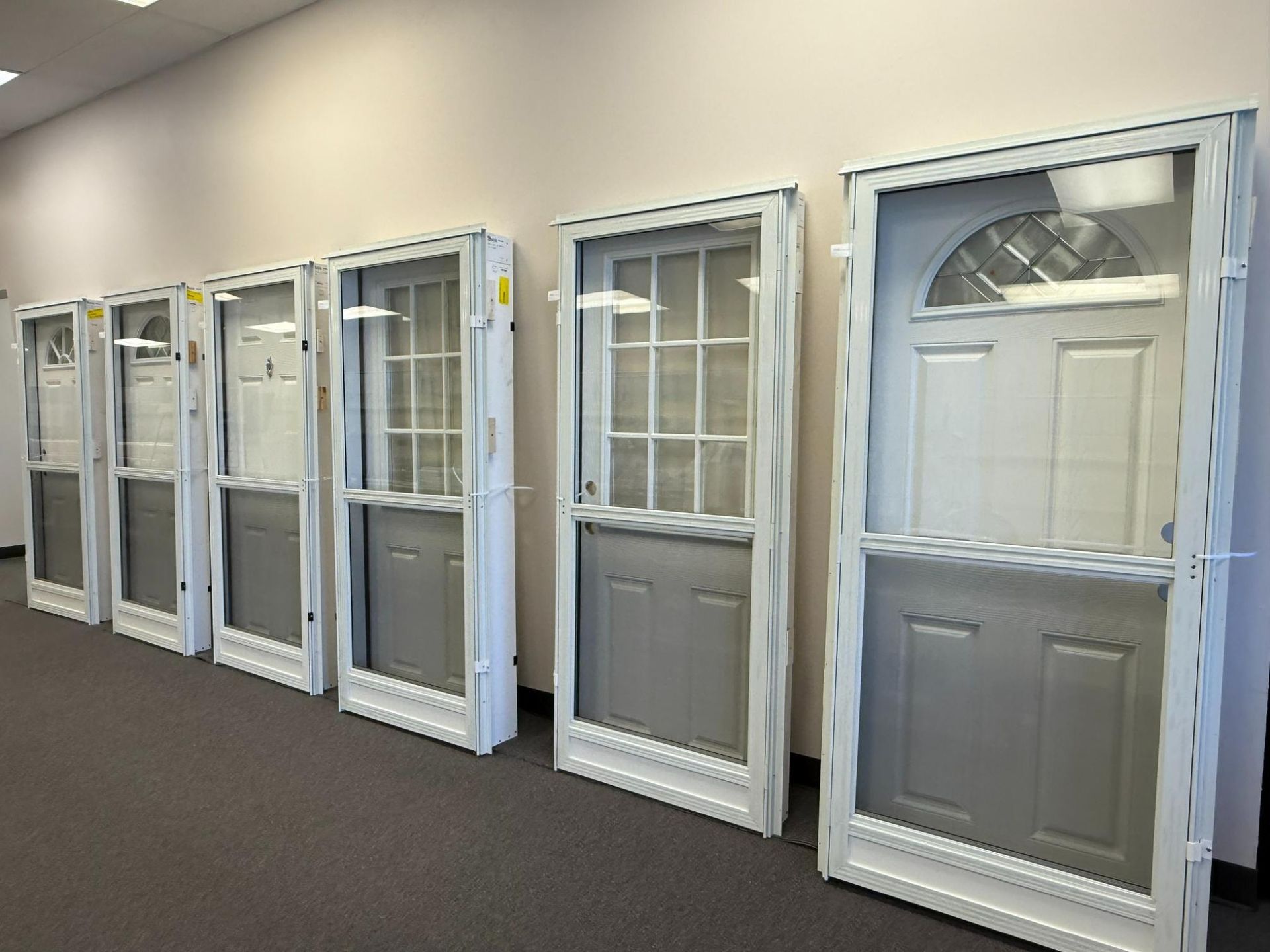 Line of white framed screen doors with gray panels, indoor setting.