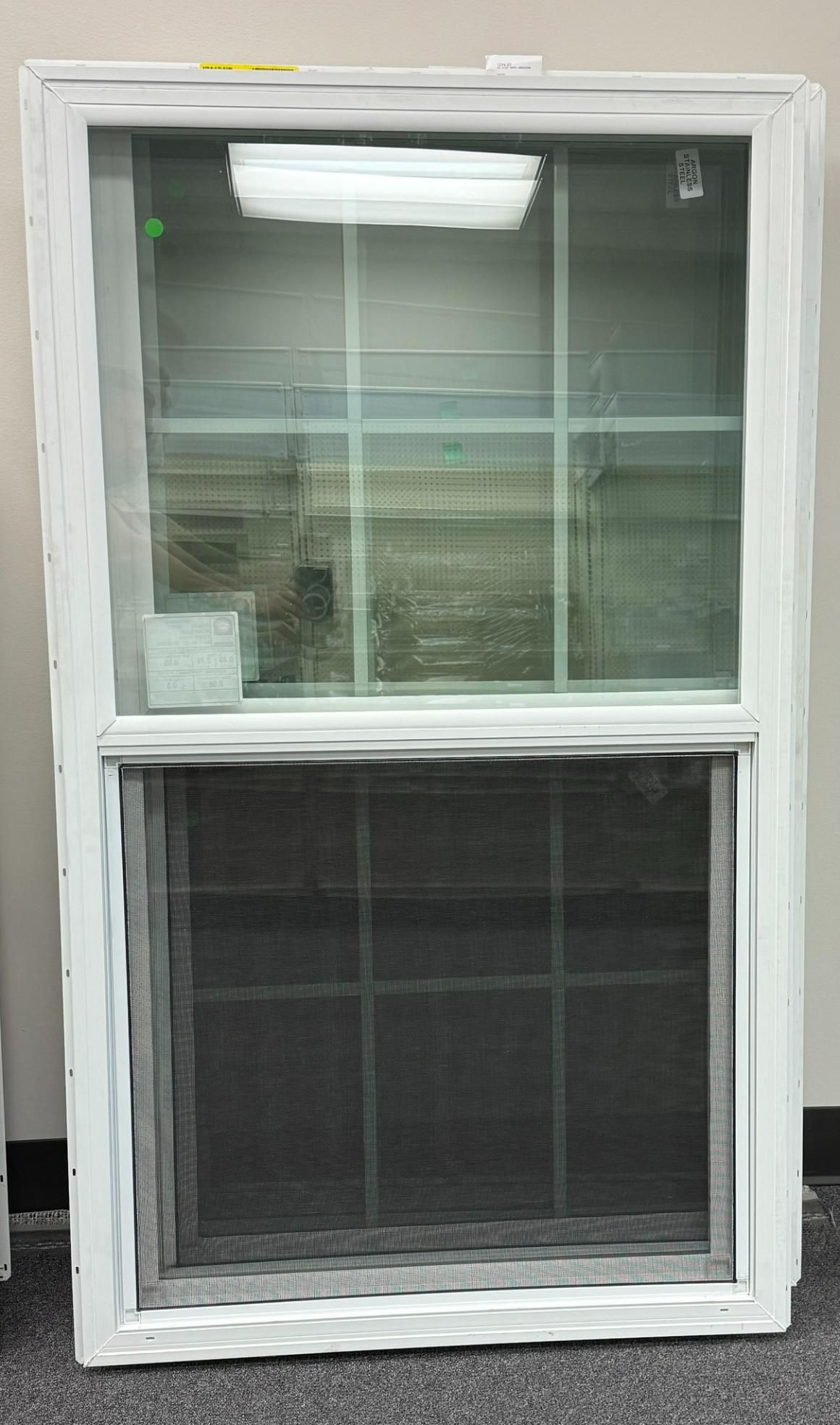 White vertical sliding window with a screen on the bottom half, showcasing grid patterns within the glass panes.
