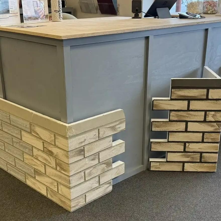 A counter with gray base and sample brick paneling in a store.