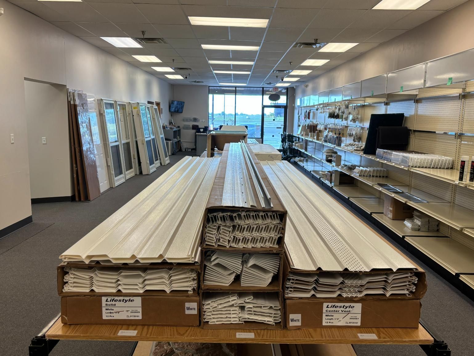 A retail store with window blinds, shelves with products, and a table displaying merchandise.