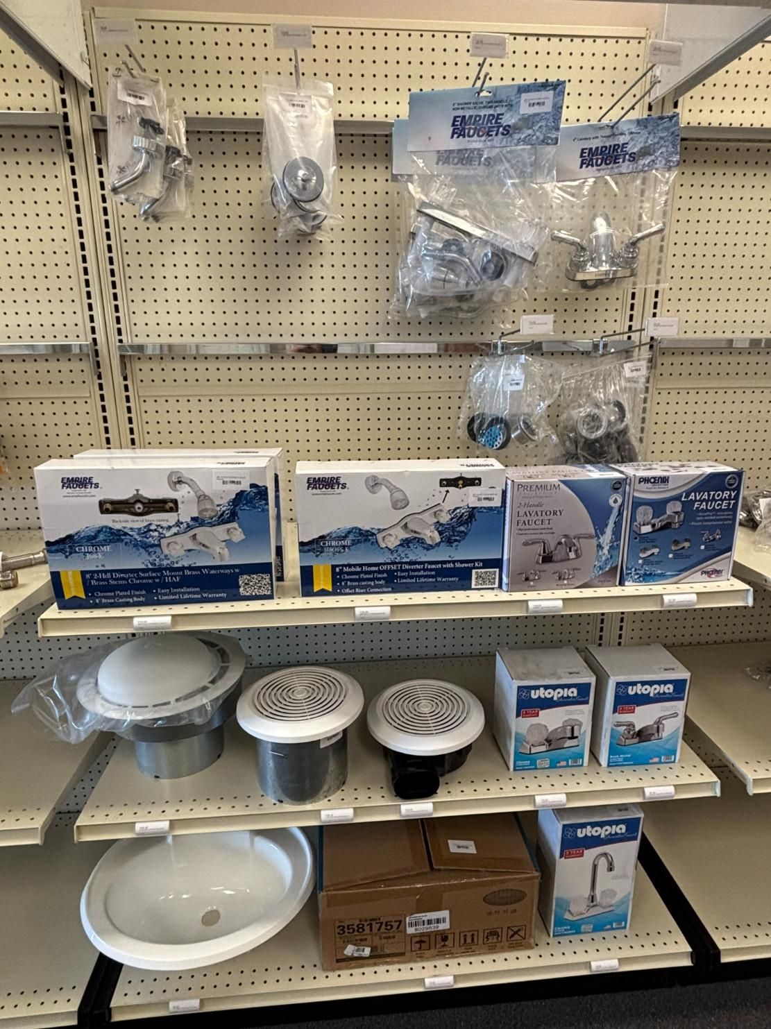 Shelves stocked with plumbing fixtures in a retail store. Includes faucets, drains, and sinks.
