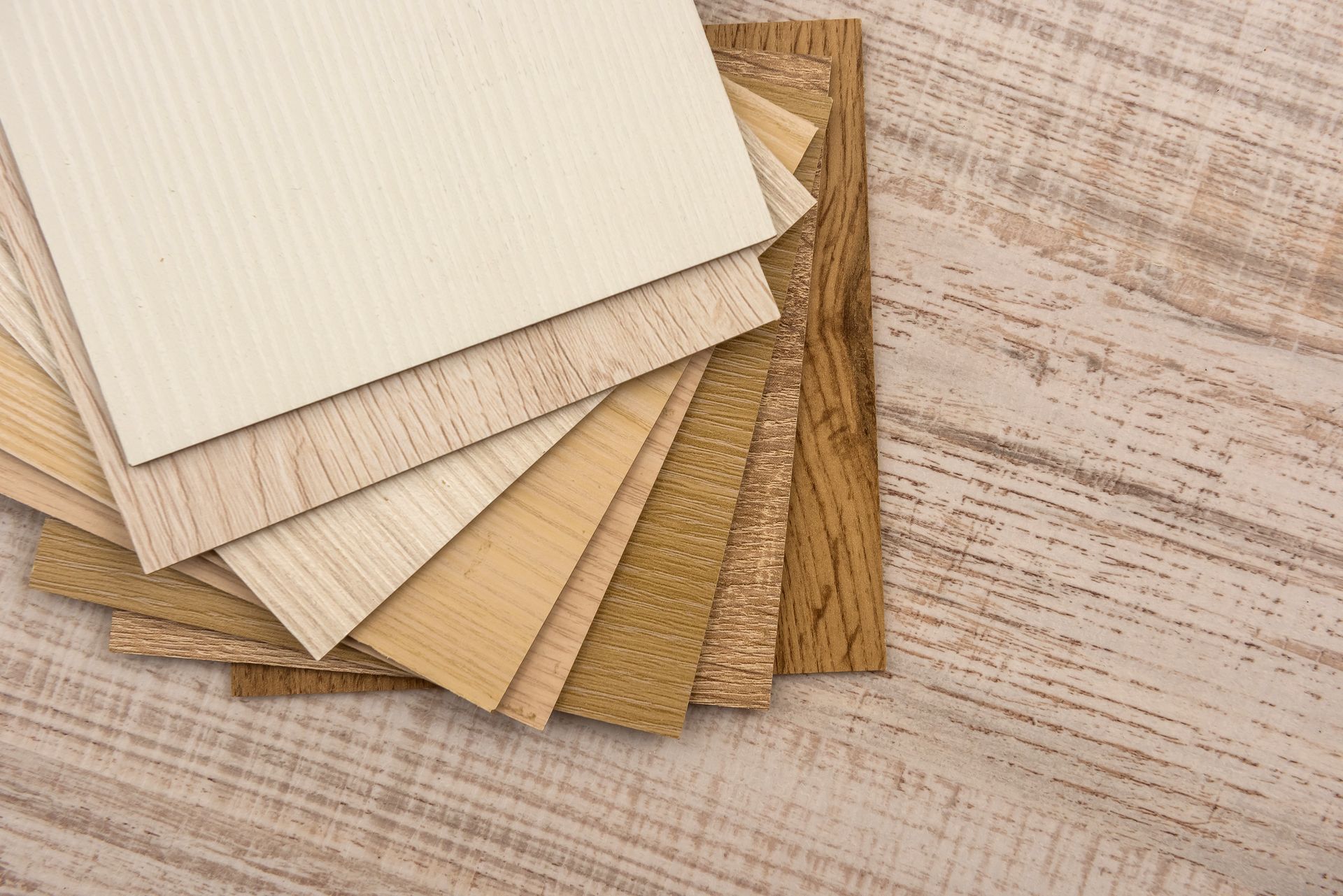 Wood samples in varying light brown tones on a light wood surface.
