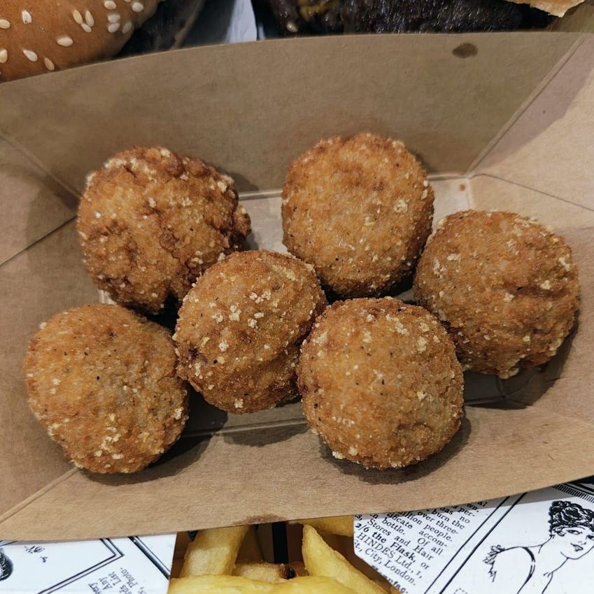 Sei polpette fritte impanate in un vassoio di carta da asporto.
