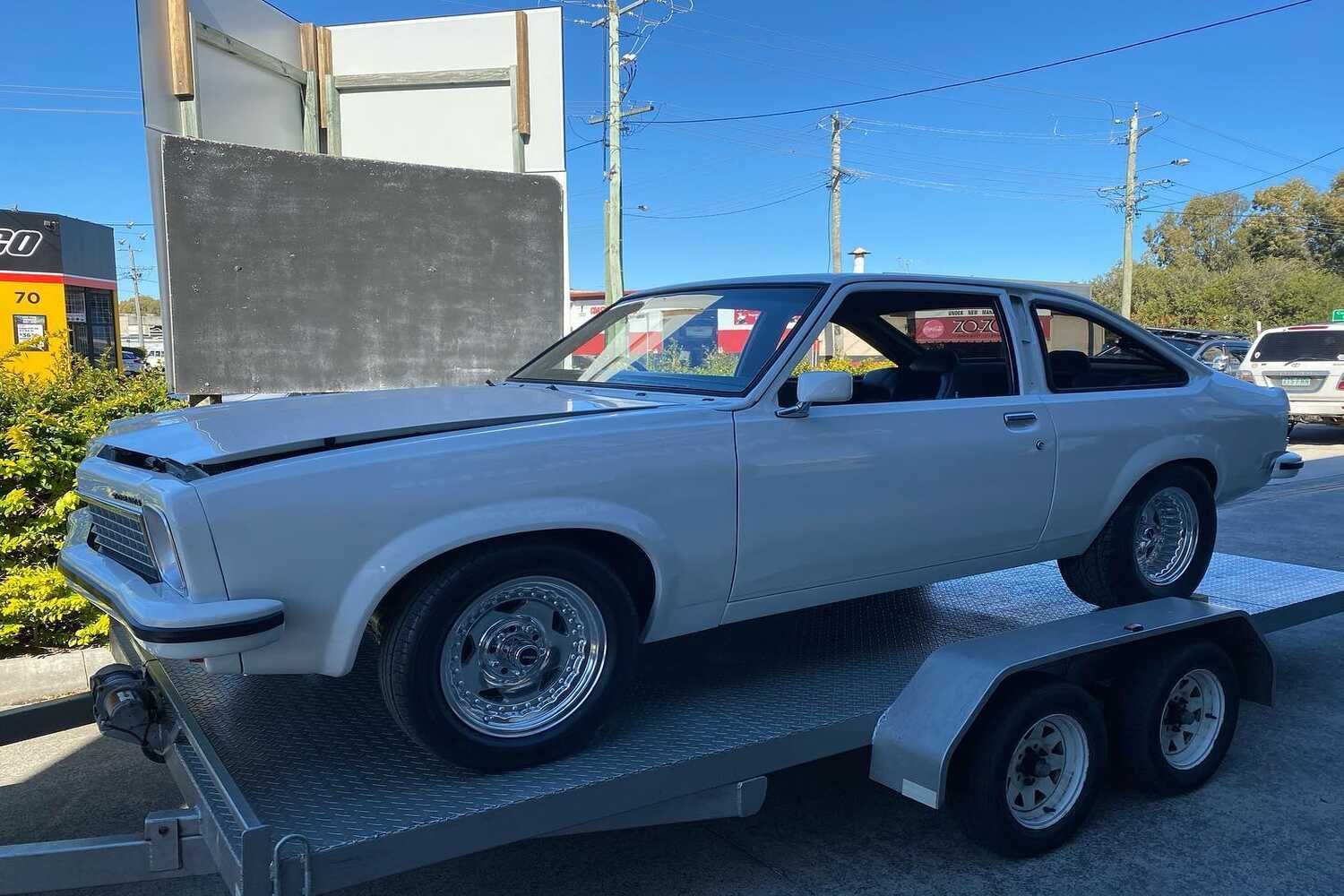 A White Car Is Sitting On Top Of A Trailer — Currumbin Trimmers  In Currumbin Waters, QLD