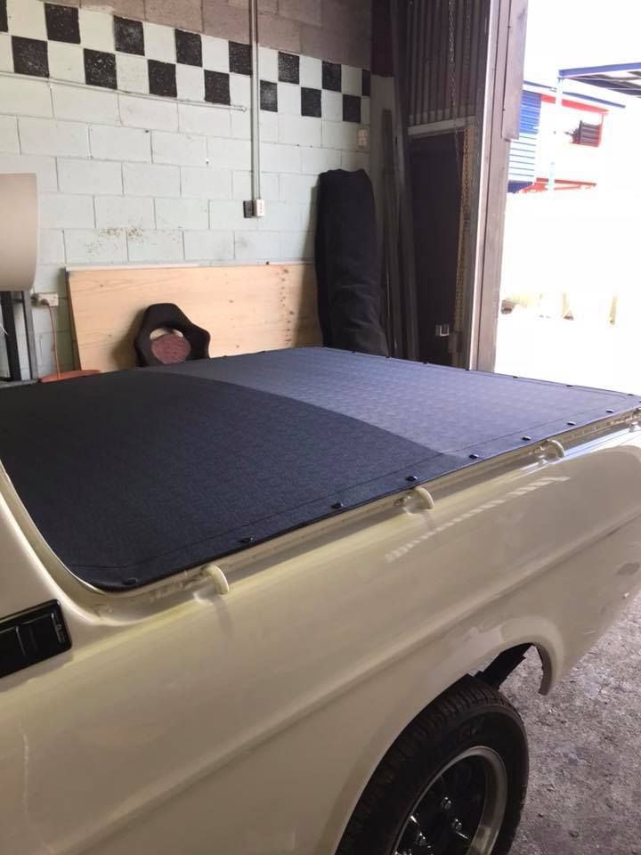 A White Truck With a Black Tonneau Cover is Parked in a Garage — Currumbin Trimmers In Kingscliff, NSW