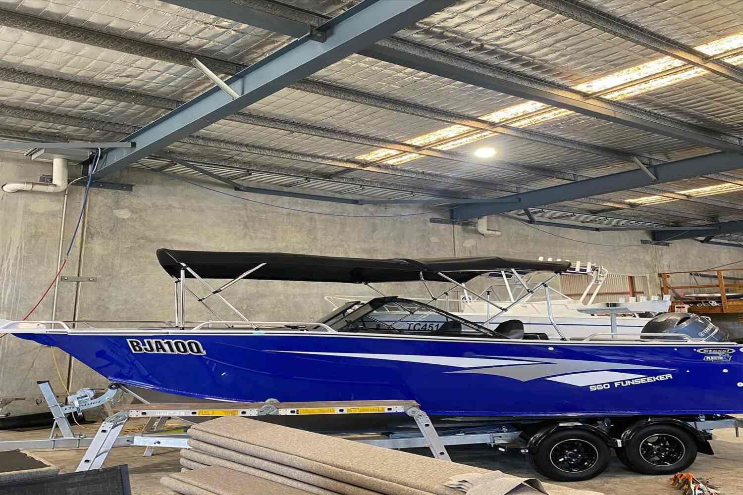 A Blue Boat Is Sitting On A Trailer In A Warehouse — Currumbin Trimmers  In Currumbin Waters, QLD