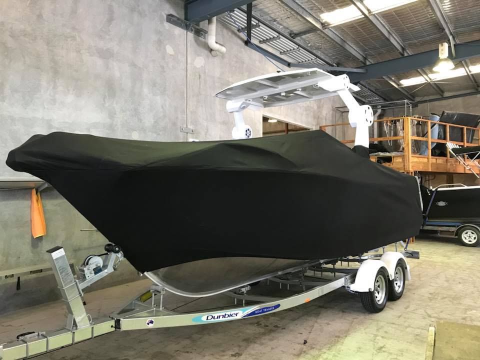 A Boat With a Black Cover on It is on a Trailer in a Warehouse — Currumbin Trimmers In Kingscliff, NSW