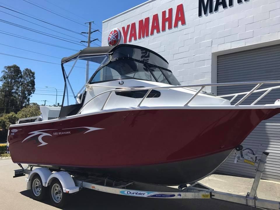 A Red and White Boat is Parked in Front of a Yamaha Building — Currumbin Trimmers In Burleigh Heads, QLD